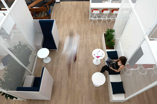 An office space with several seating areas and a woman reading a magazine on a bench 