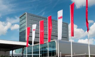 Rode en witte vlaggen met het logo van Rai Amsterdam die staan voor het gebouw