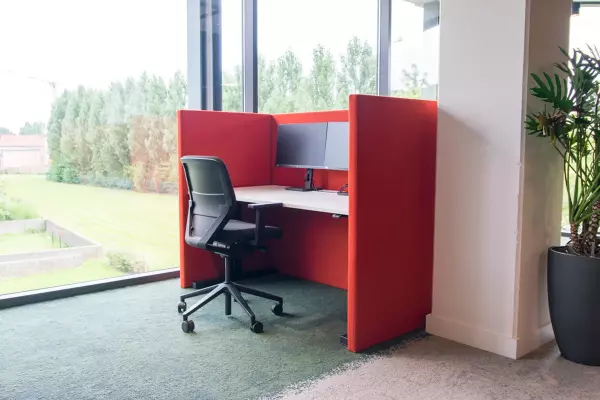 Zit-sta bureau met ergonomische bureaustoel en rode akoestische wanden